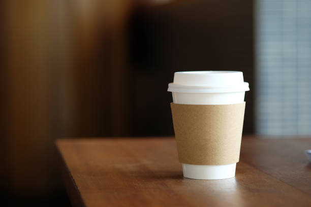 Coffee paper cup on wood table in coffee cafe.