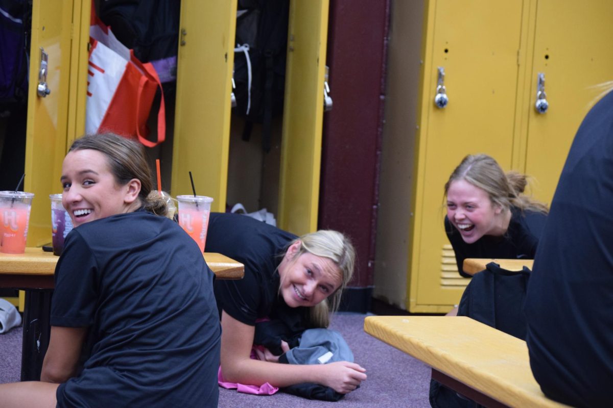 Anne Grant, Siri Beecher, and Ashley Staun laugh in the locker room while pregaming.
