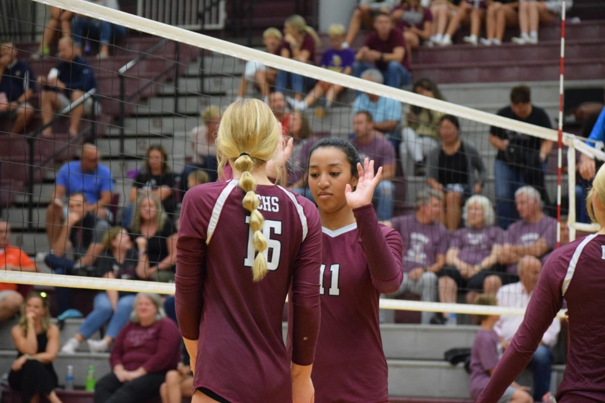 Kaylie Klein and Amaiya Thompson high-five each other before the next serve.