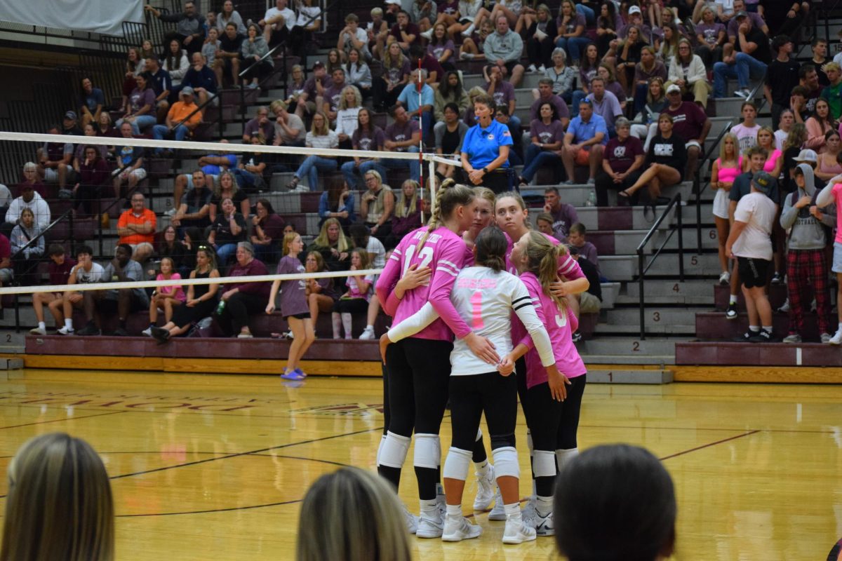 The girls on the court huddle after winning a point. 
