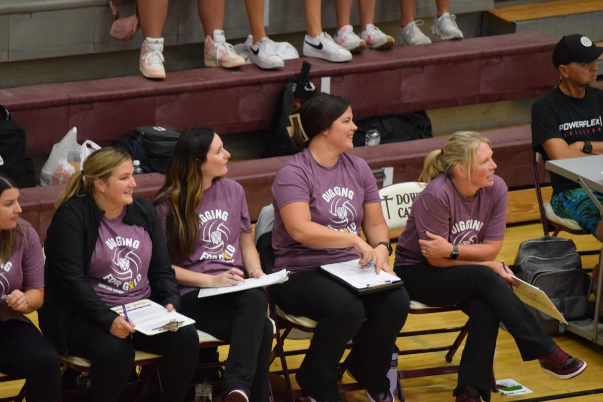 Coach Jesse Proehl, Coach Leigha McQuade, Coach Marci Schrage, and Coach Mary Beth Wiskus sit on the sidelines during the Waukee game.