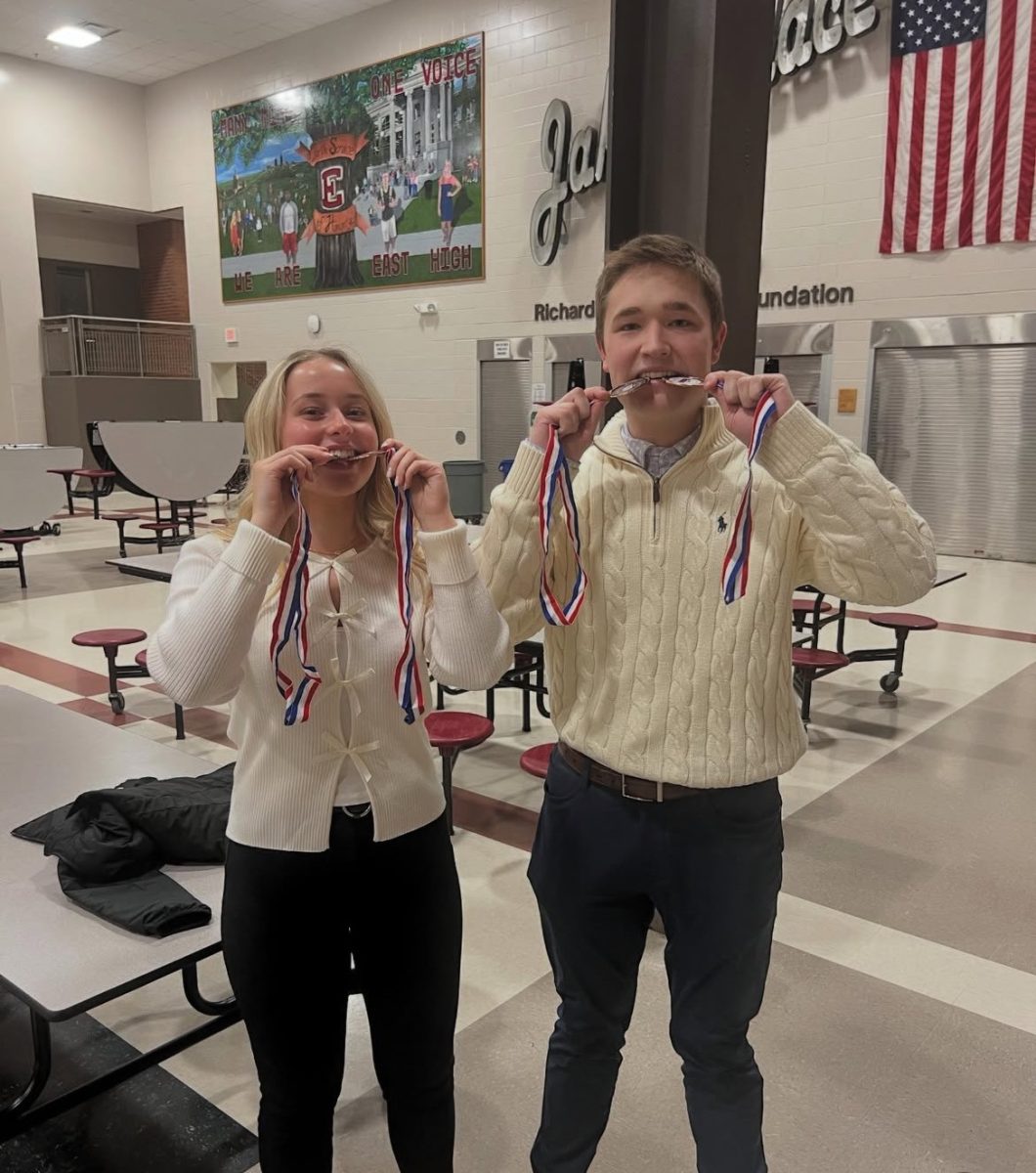 Nora Romain and Leo Klemm biting their medals.