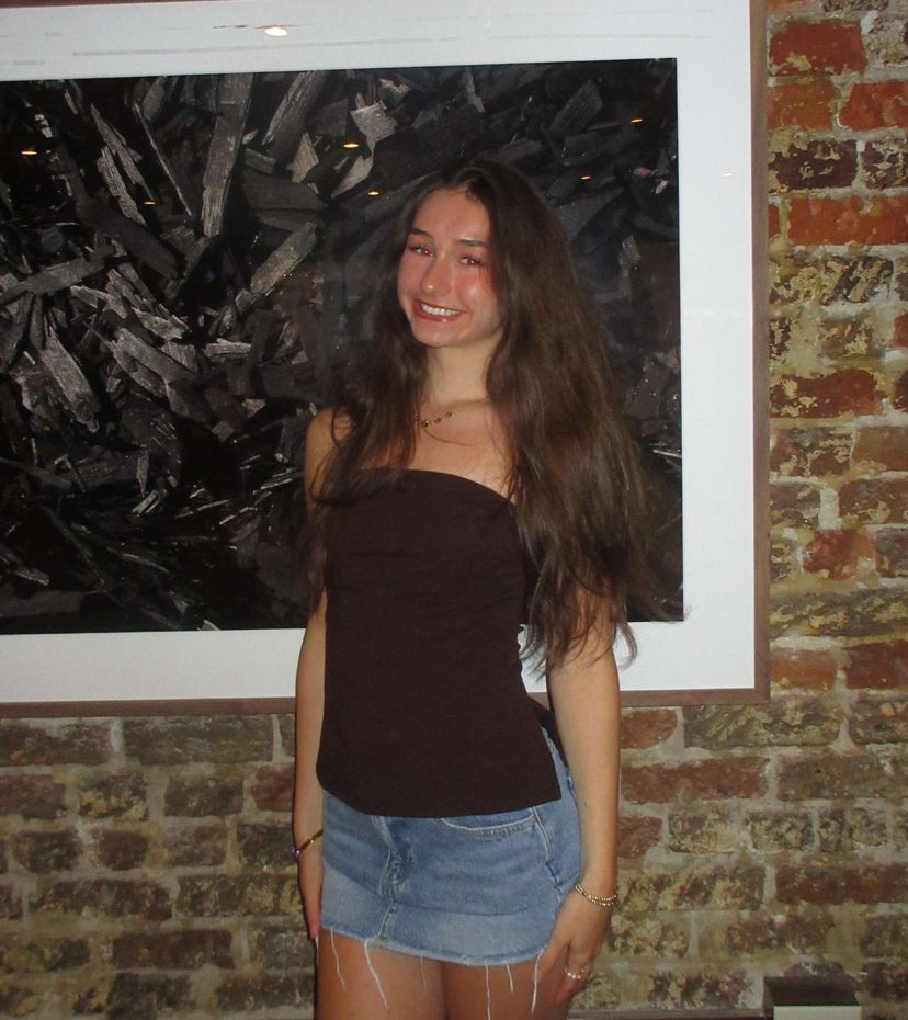 Eva smiles in front of a brick wall in Savannah, Georgia.