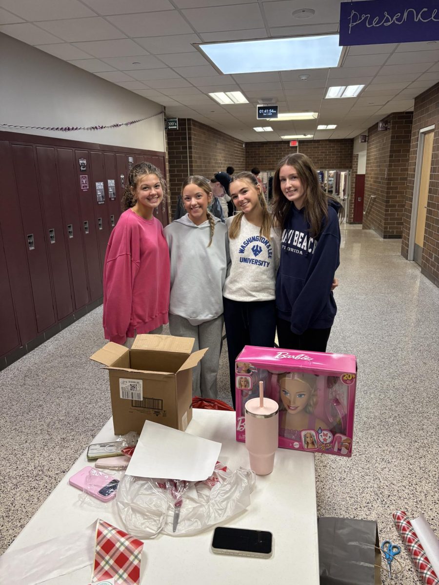 Anna Rauen and her group smile for a picture in-between wrapping presents. 
