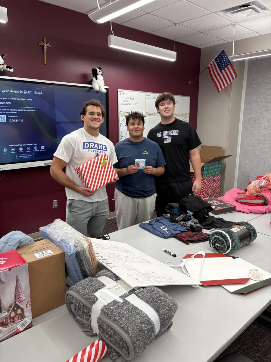 Ryan Bobo, Cesar Duran, and Josh Miller take a picture holding their gifts that they have wrapped.