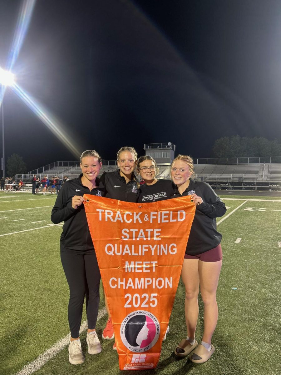 Cora Volp (11), Ava Van Ee ('25), Jennifer Stacy (12), and Braelyn Gifford ('25) grab a photo together with the State Qualifying meet Champion Banner.