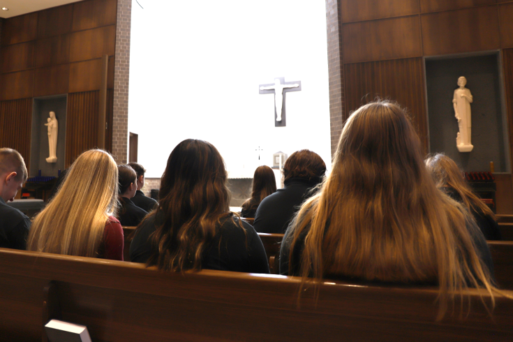 Dowling Catholic students sit quietly praying with their classmates and teachers.